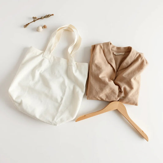 Neatly folded natural-fabric garments and fabric swatches arranged on a minimalist light background