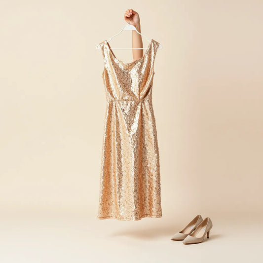 Sparkly sequin party dress displayed on a hanger with evening accessories on a clean studio backdrop
